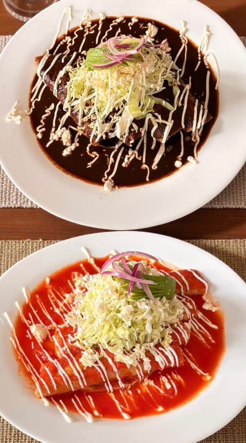 Two plates of okonomiyaki topped with shredded cabbage, green onions, and drizzled sauce