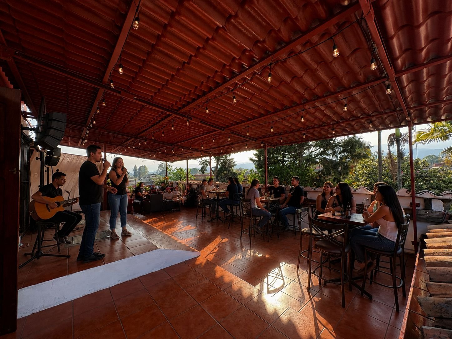 Indoor gathering under red wooden ceiling with natural light, people seated at tables and musician with guitar performing
